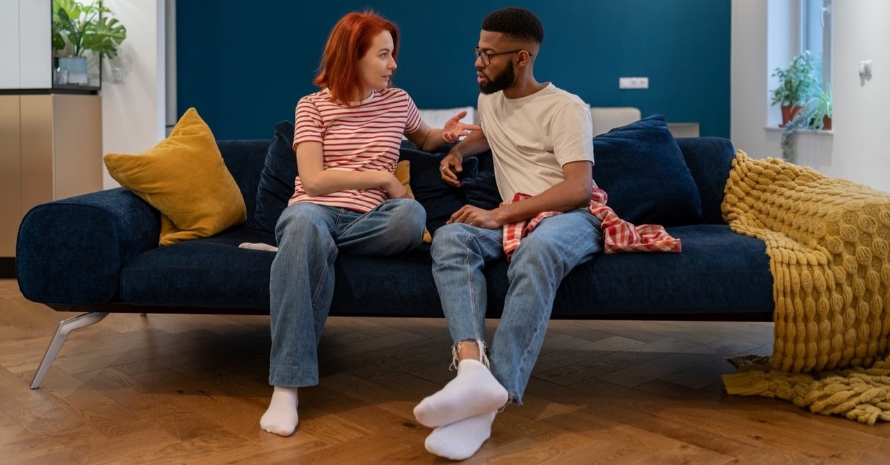 biracial couple talking on couch, signs your marriage needs more quality time together