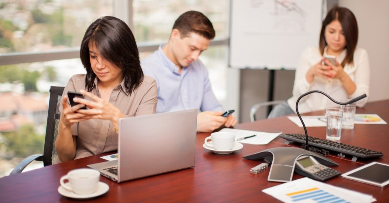 distracted people in office looking at smartphones