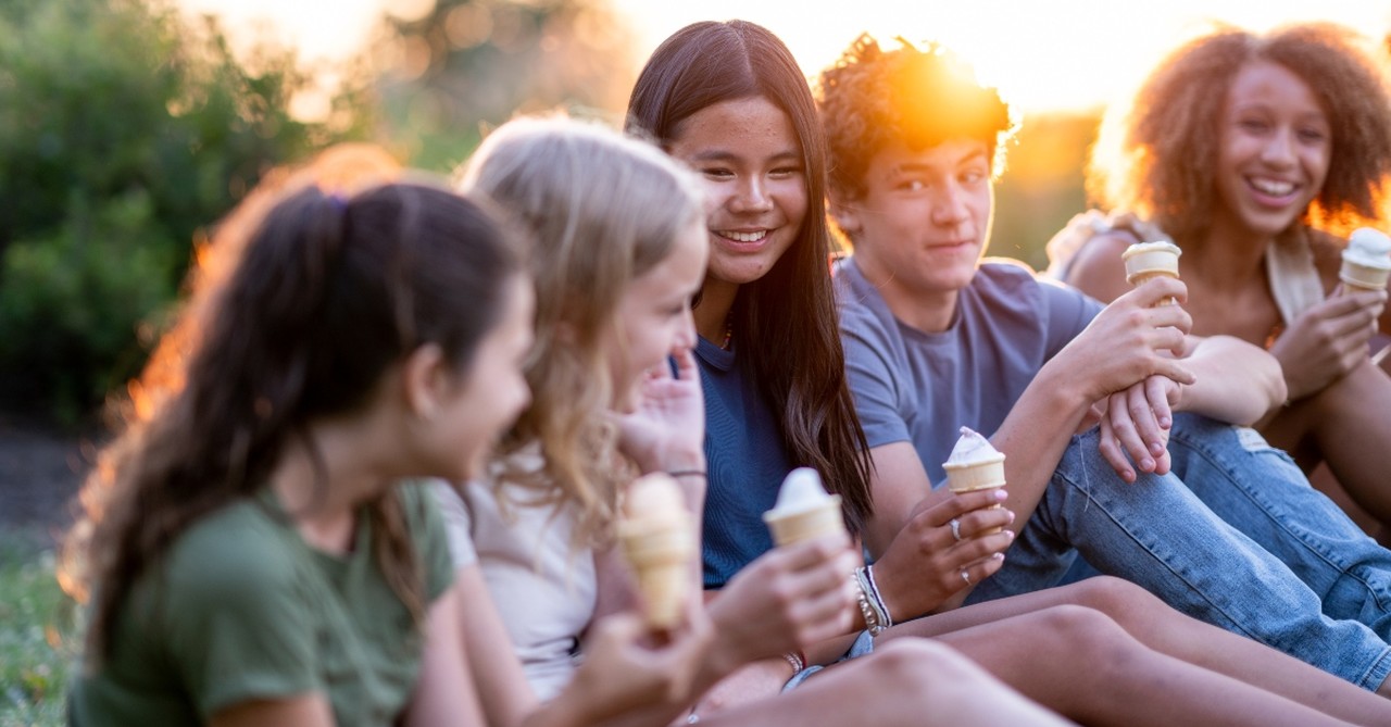 A group of young teens hanging out, eating ice cream