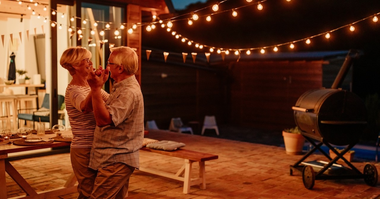 Happy older senior married couple dancing in backyard