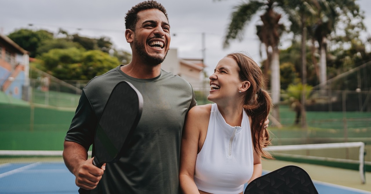 Happy laughing couple date night playing pickleball sporty