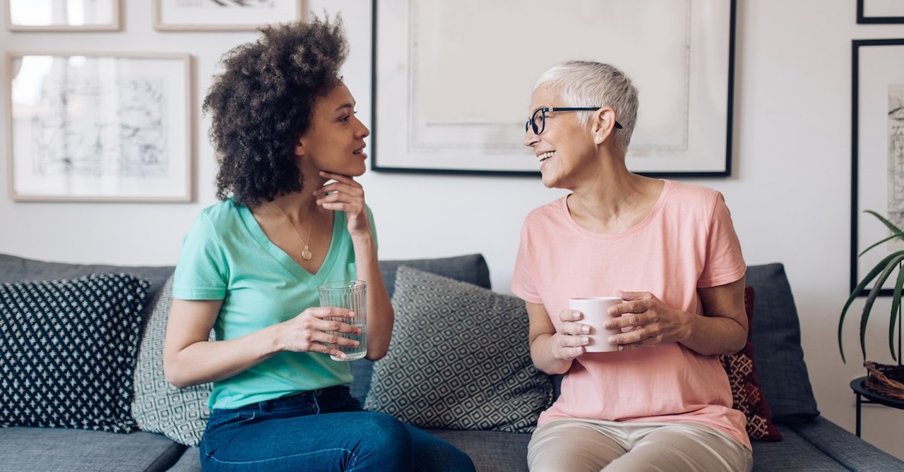 Senior woman talking with adult woman on couch mentor mugs