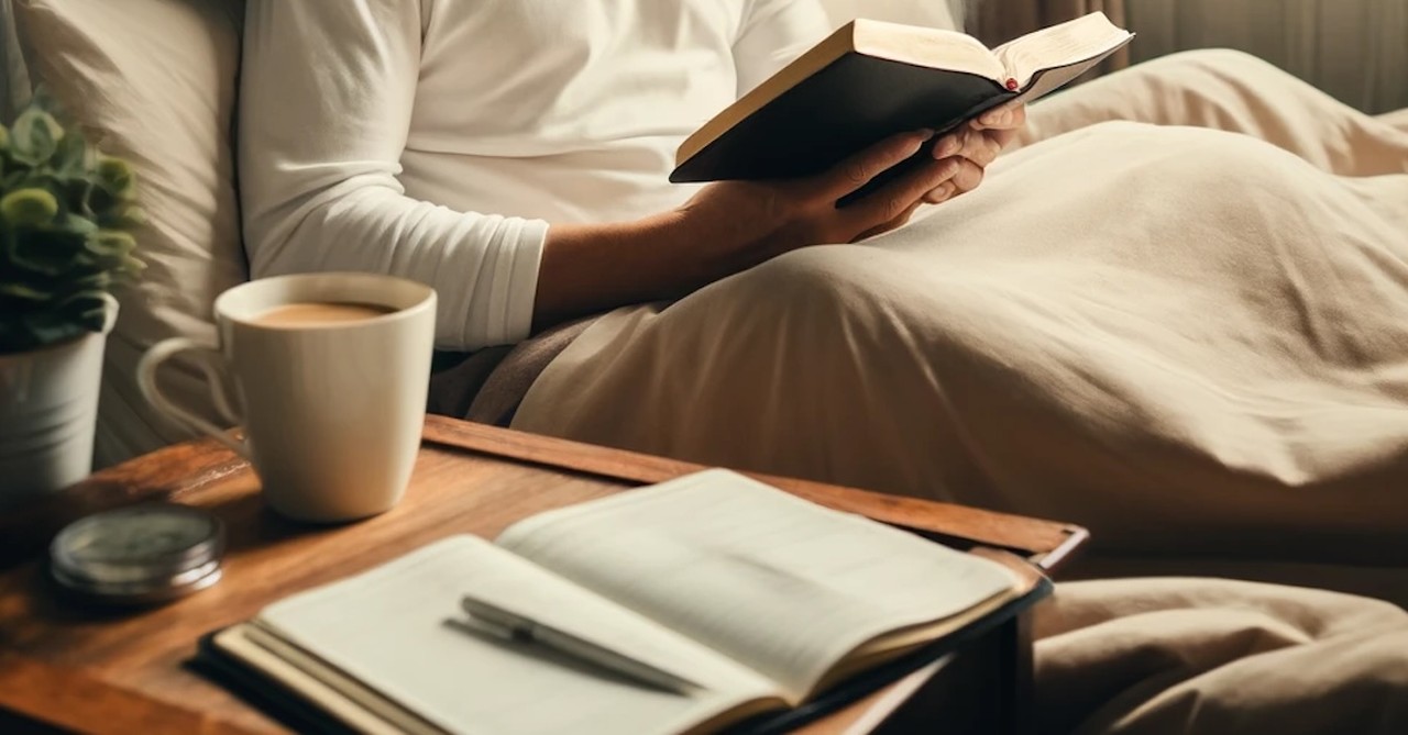 Man reading Bible quiet time in bed with notebook and coffee