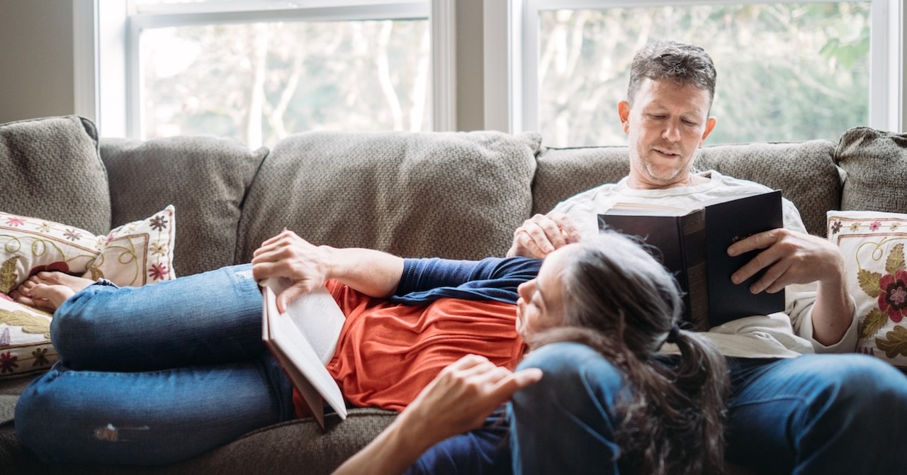 Married couple on couch resting and reading books date at home