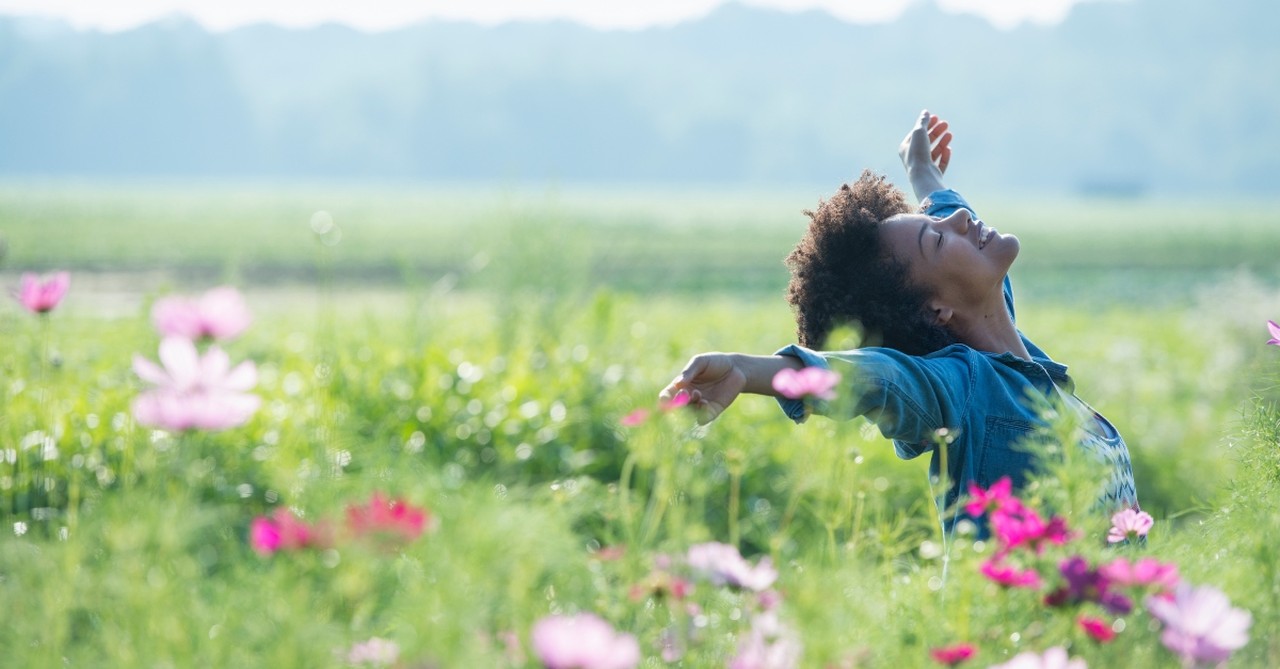 Blissful woman lifting her hands in a field of flowers; God's provision