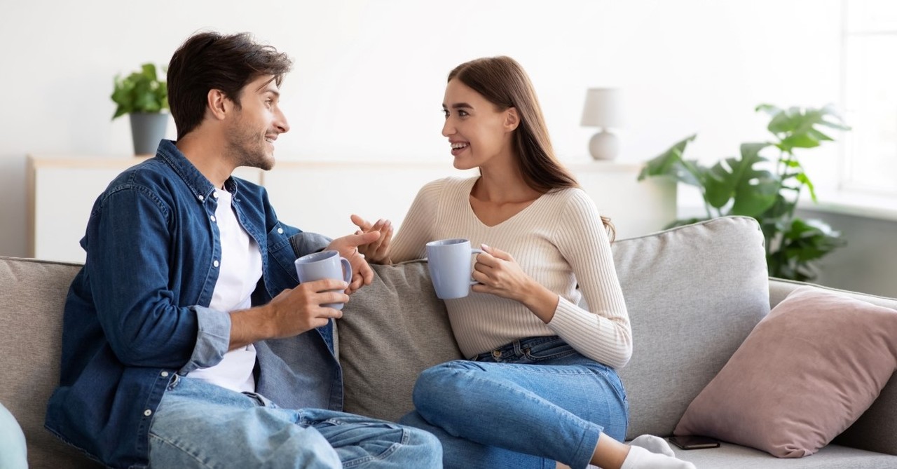 happy couple talking to each other while sitting on a couch