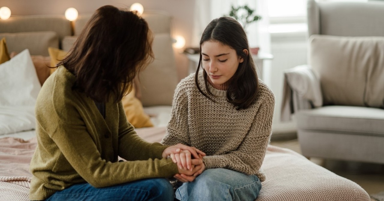 mother and teenage daughter talking while holding hands