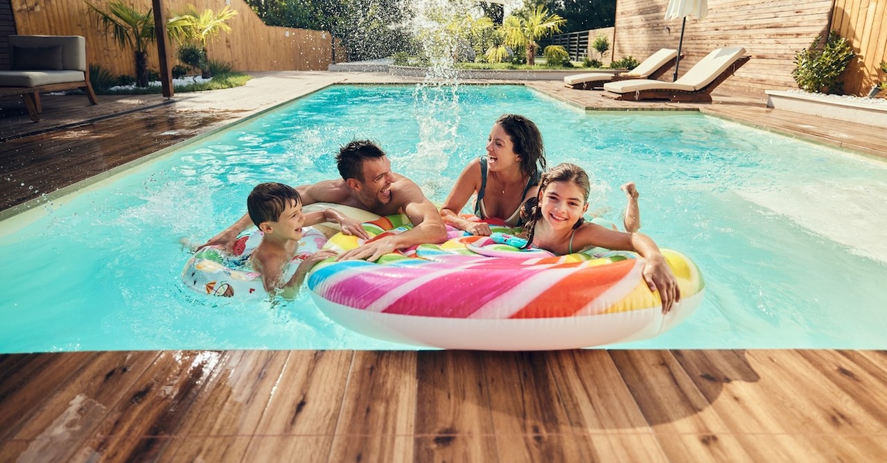 Happy family parents and kids in pool summer