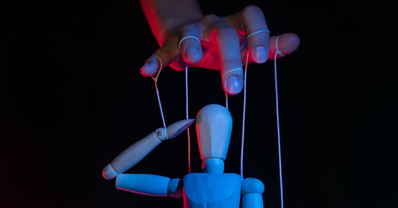 Cult hand controlling figure pulling strings