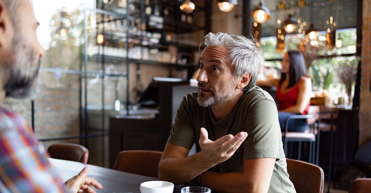 Man explaining defending faith talking to friend in coffee shop