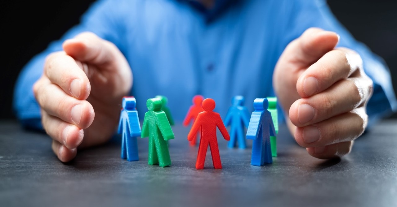 man holding hands around plastic people to illustrate selfish pastor, warning signs of a narcissistic pastor