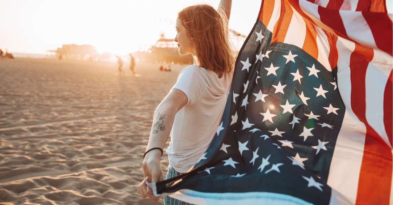 Woman with an American flag on the beach; can we love God and country?