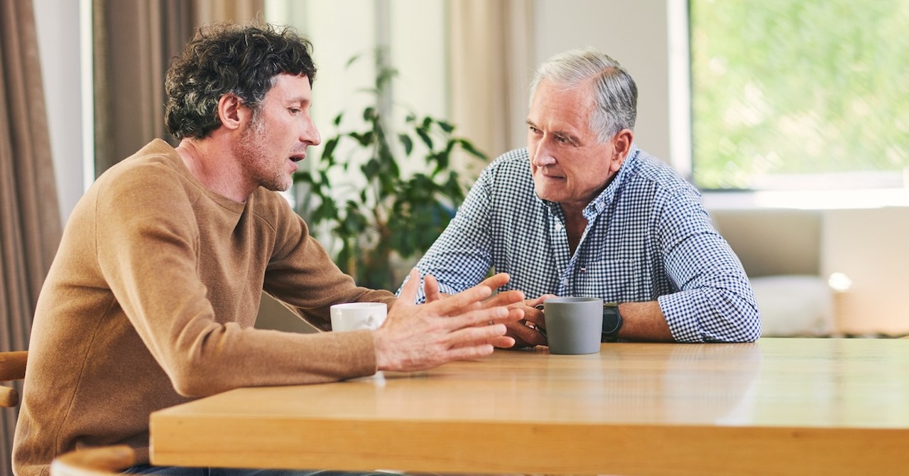 Senior dad with adult child son serious talking at table boundaries