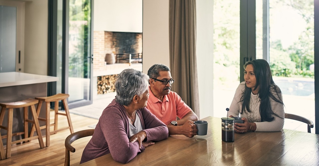 Parents talking to adult daughter at table serious setting boundaries