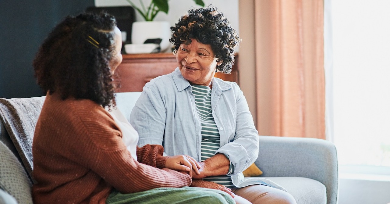 Senior mom talking to adult daughter on couch at home setting boundaries