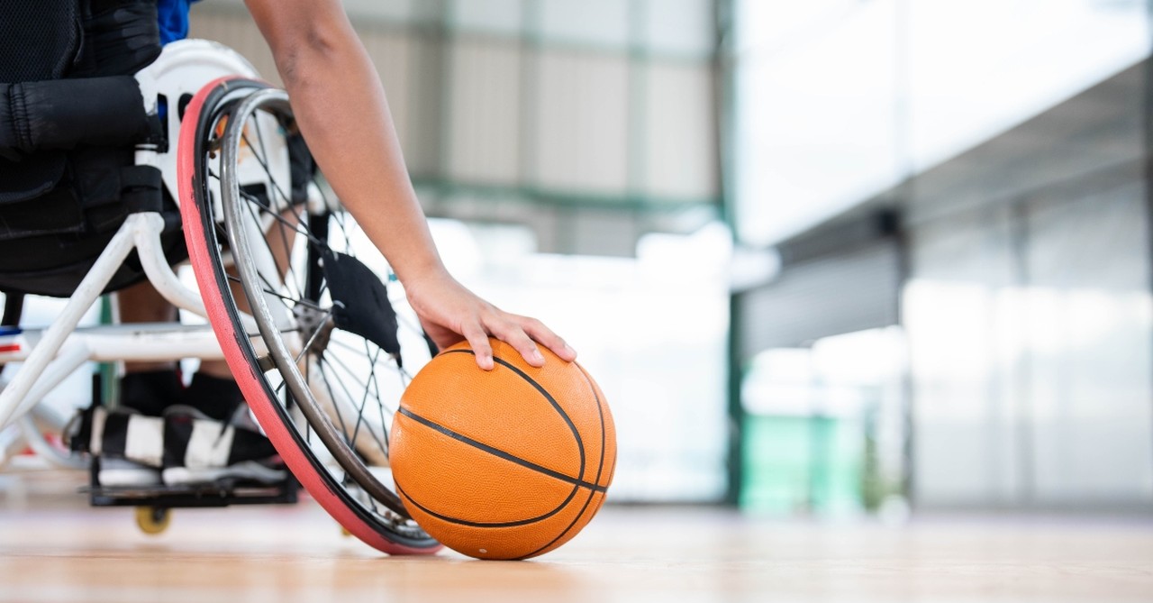 A wheelchair user holding a basketball on the court