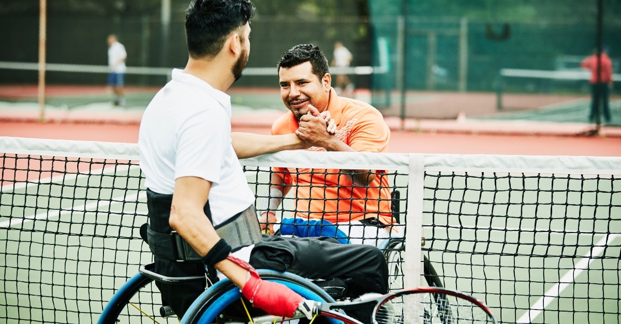 Two men in wheelchairs shaking hands after a tennis match