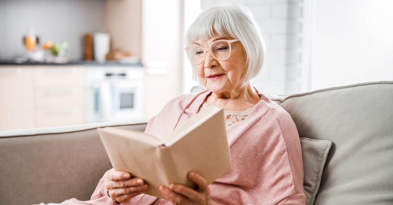 Senior woman reading book on couch