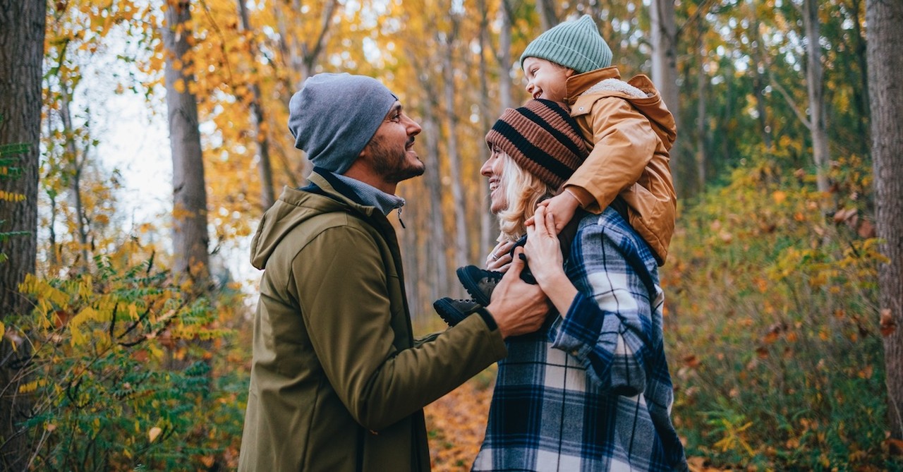 Happy family on trail fall leaves parents with child