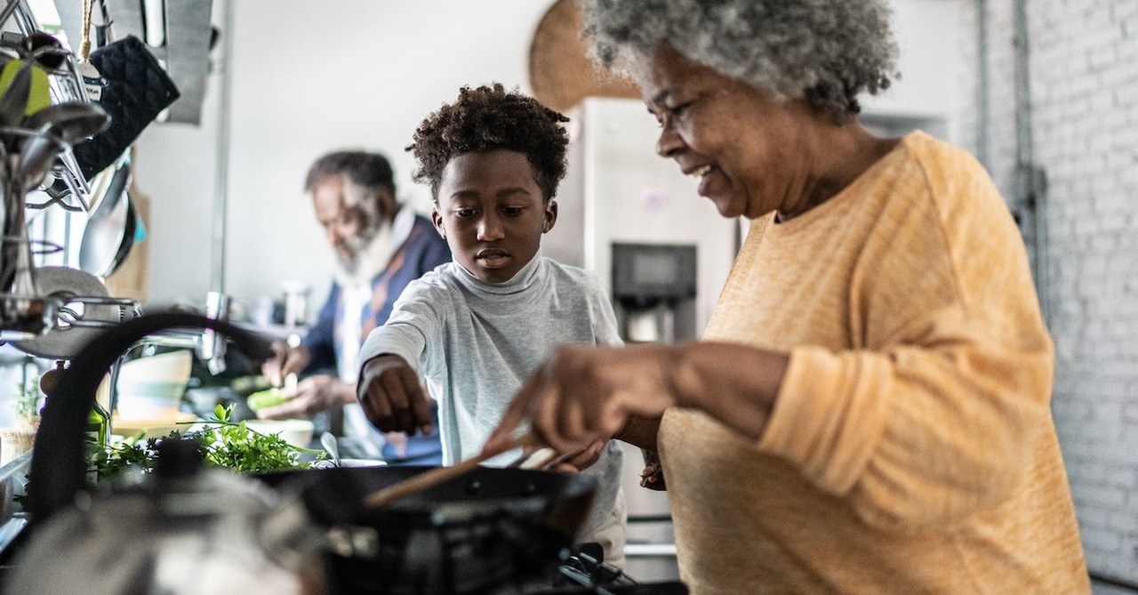 Grandma cooking soup in kitchen with grandson