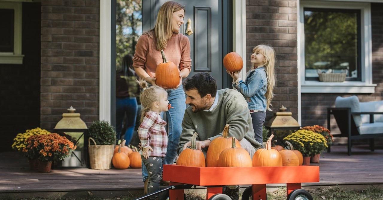 Family parents and kids decorating house porch for fall pumpkins