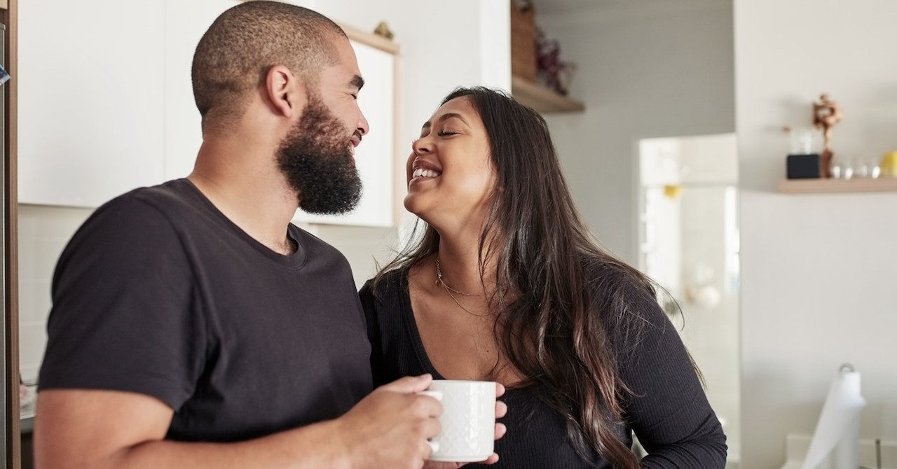 Happy couple in kitchen drinking coffee talking