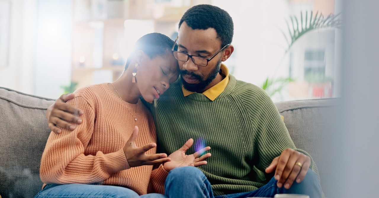 Worried couple husband comforting wife on couch