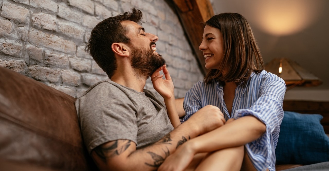 Happy married couple laughing on couch intimacy