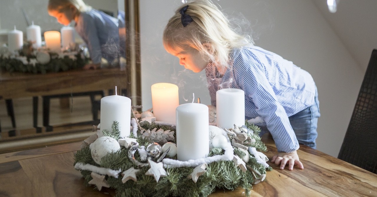 Little girl blowing out Advent christmas candles