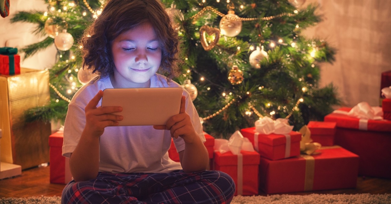 Child playing video games by a Christmas tree