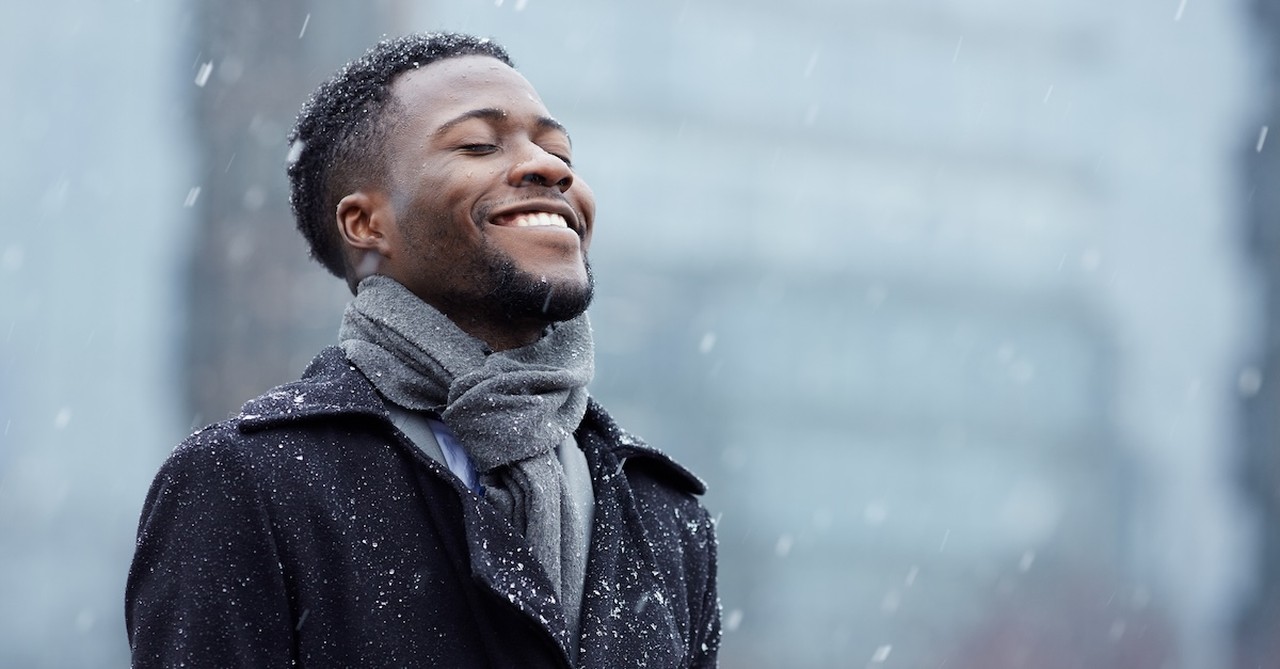 Happy single man smiling in city winter snow Christmas