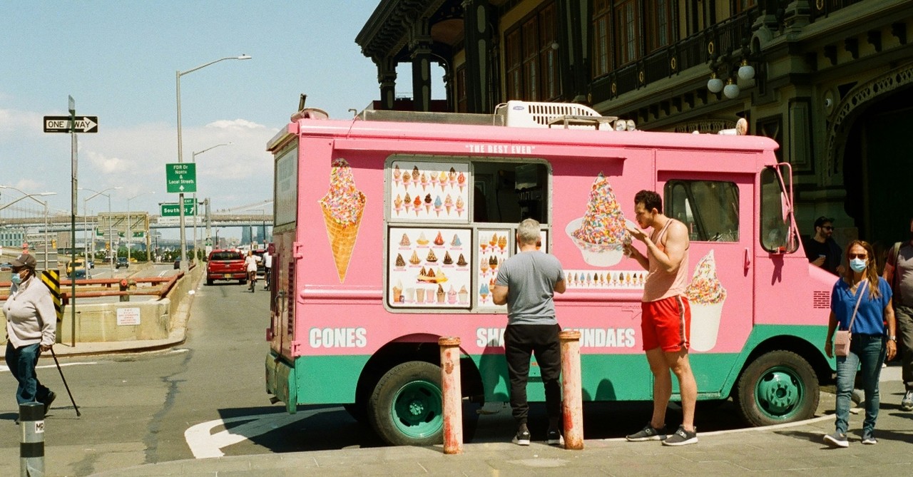 An ice cream truck on a street corner in the summer