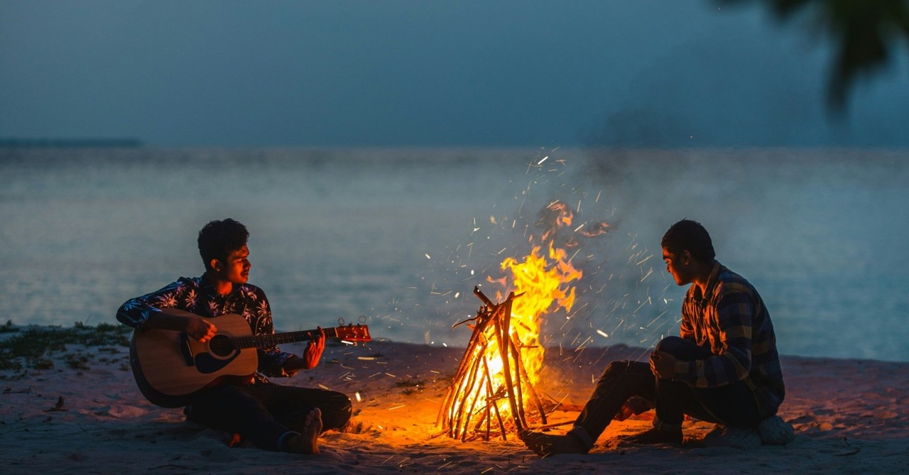 Two men sitting by a bonfire on the beach