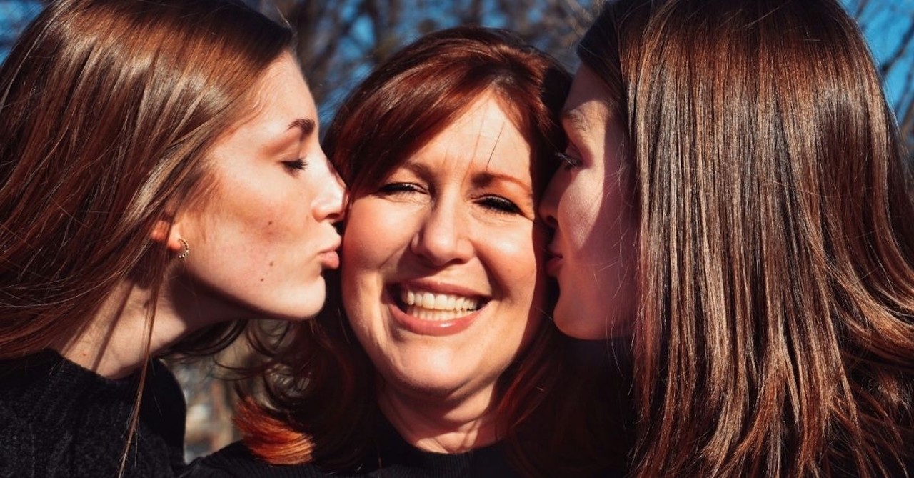 Daughters kissing their mom on the cheeks; encouraging kids of any age.