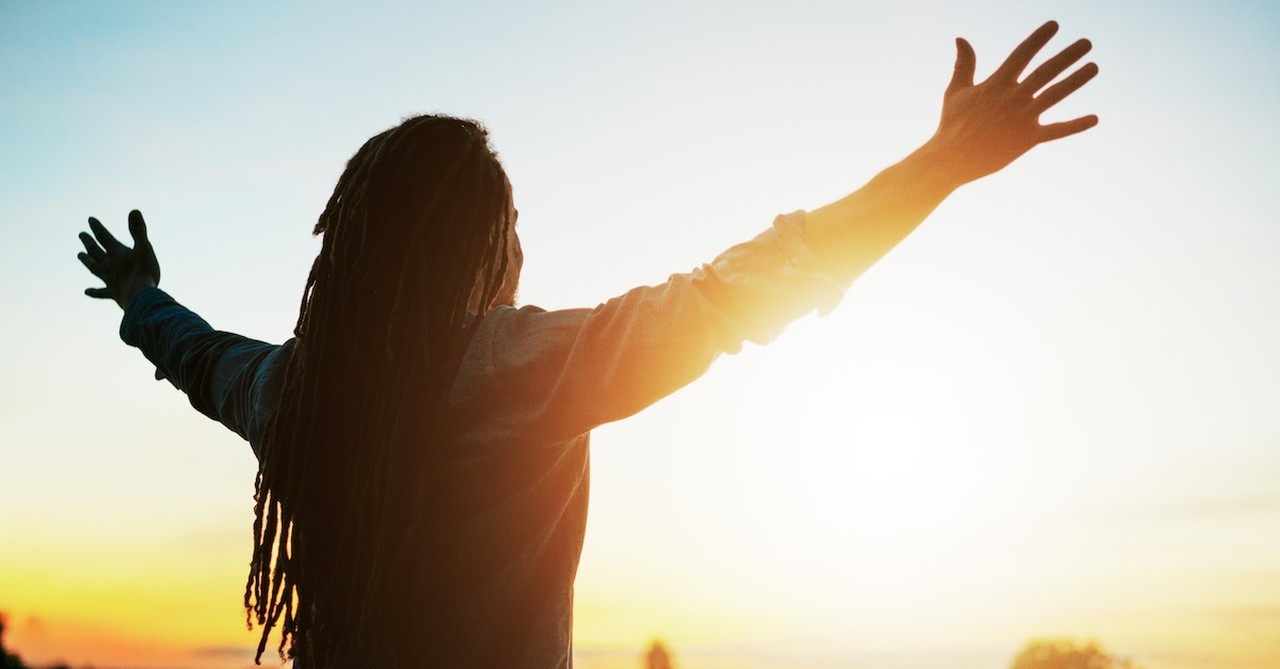 silhouette of man with raised hands at sunrise