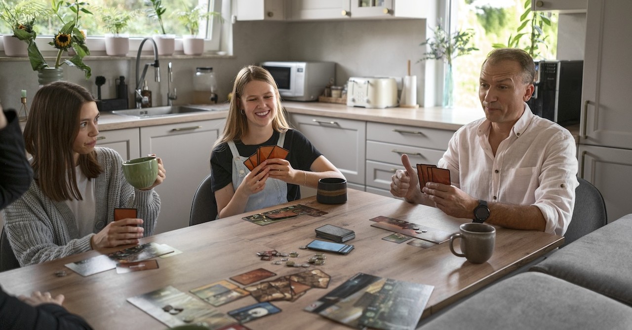 Family playing cards boardgame game night at kitchen table