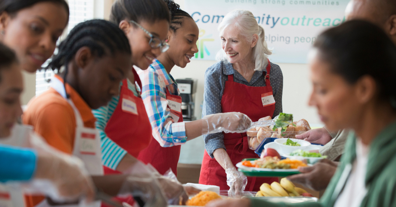 People smiling and serving in a community (like helping at a food pantry)