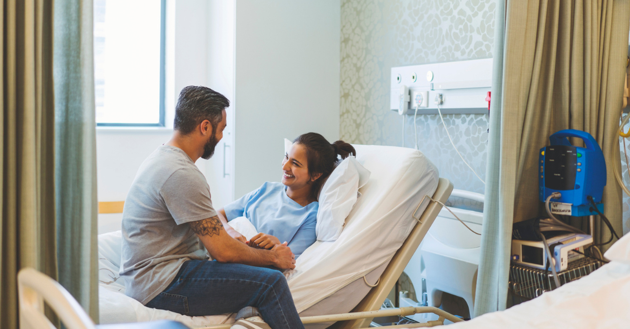 A picture of a person sitting in a hospital room beside a loved one’s bed