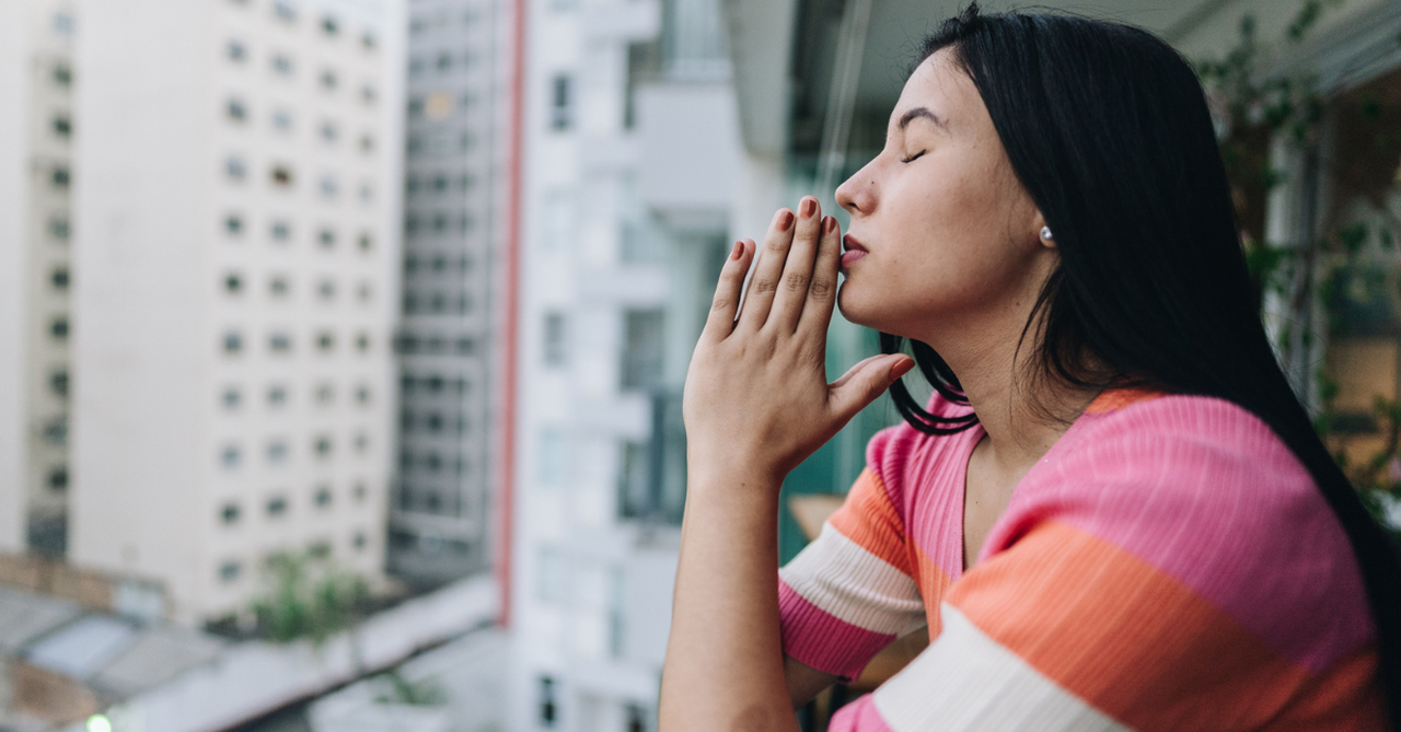 Young woman praying on the balcony at hotel