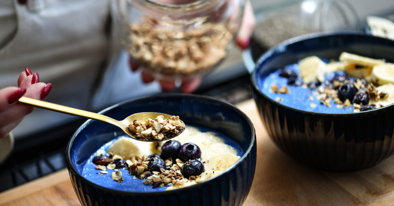 A glass jar or bowl of overnight oats with fresh berries, nuts, and a spoon.