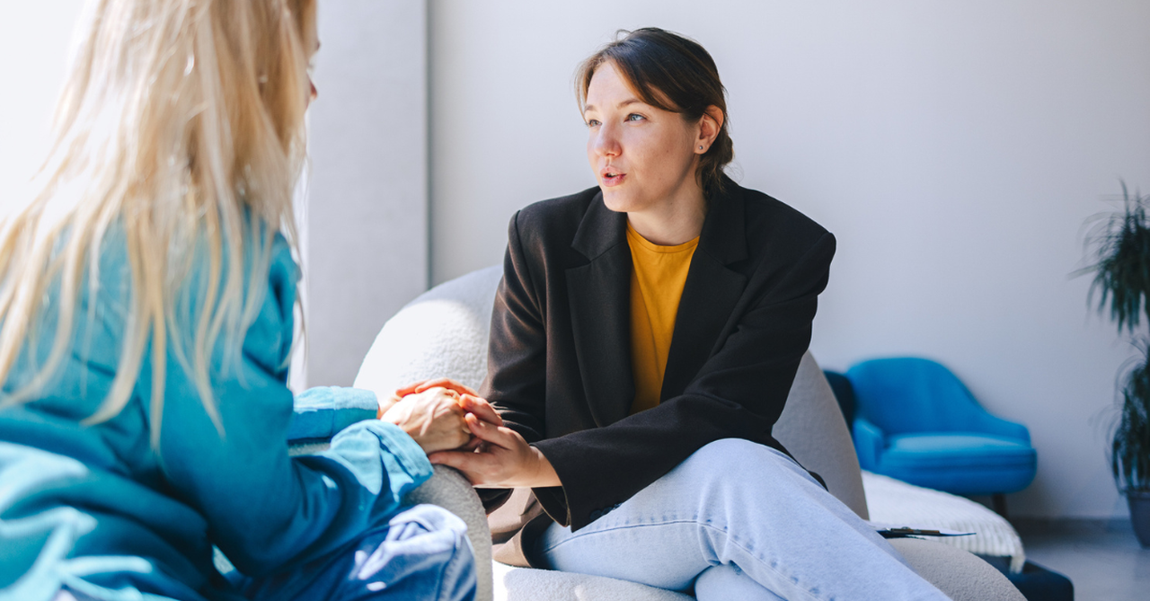 Person leaning in, listening attentively, hand on hand
