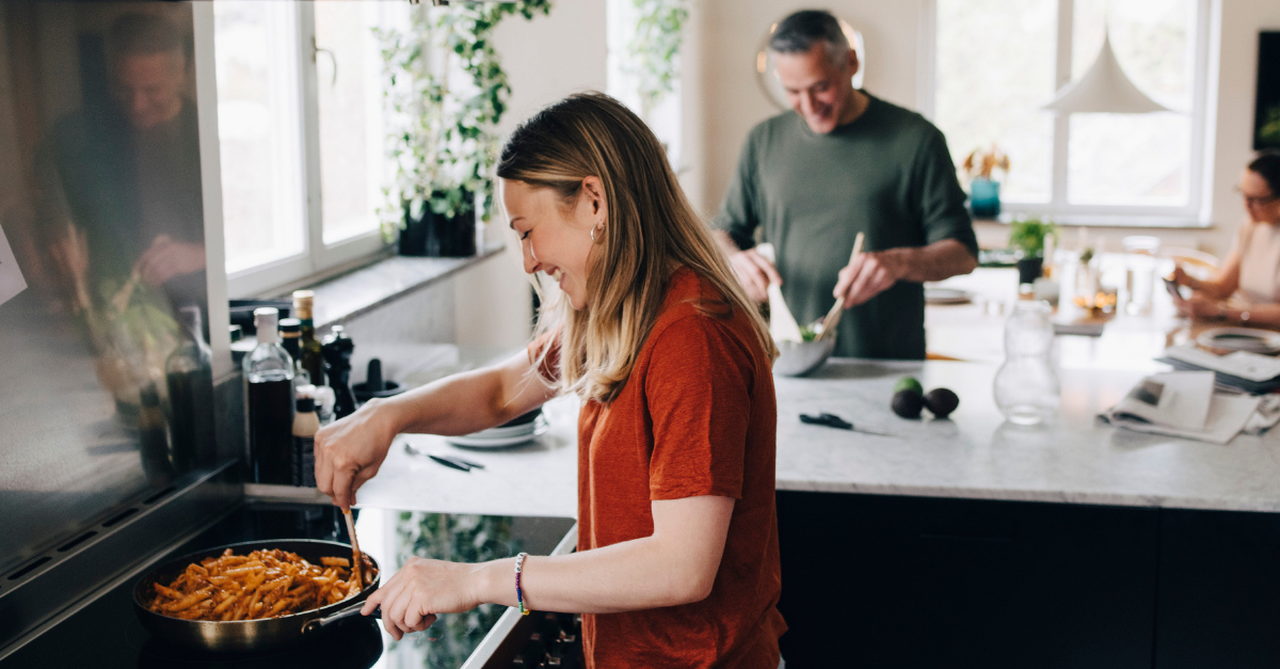Woman cooking pasta on stove in kitchen