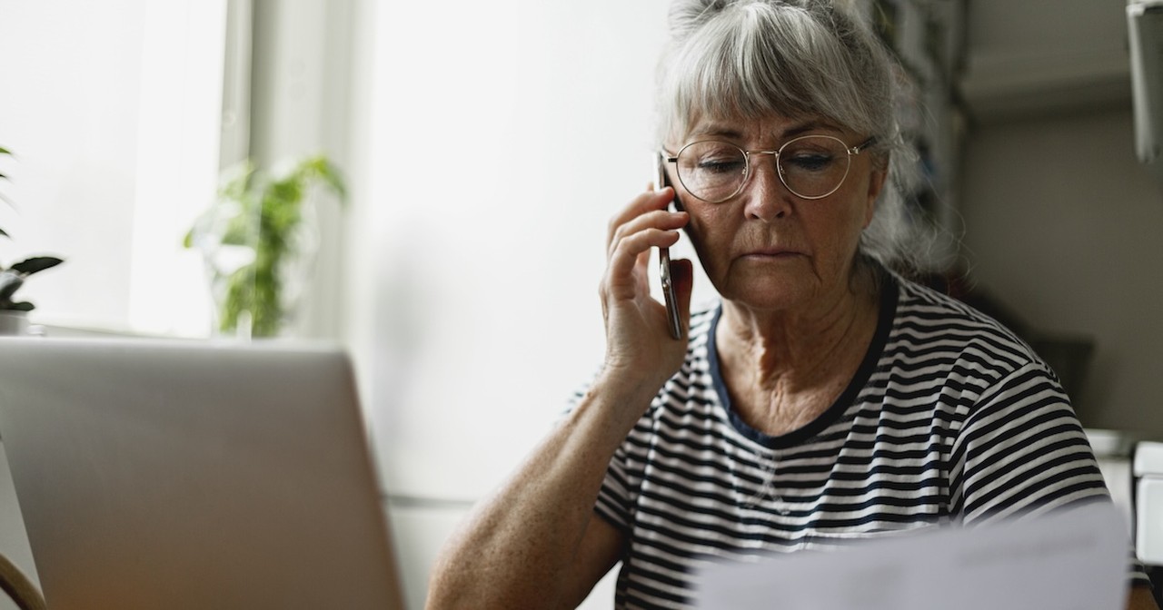 Stressed senior woman on phone call planning finances budget