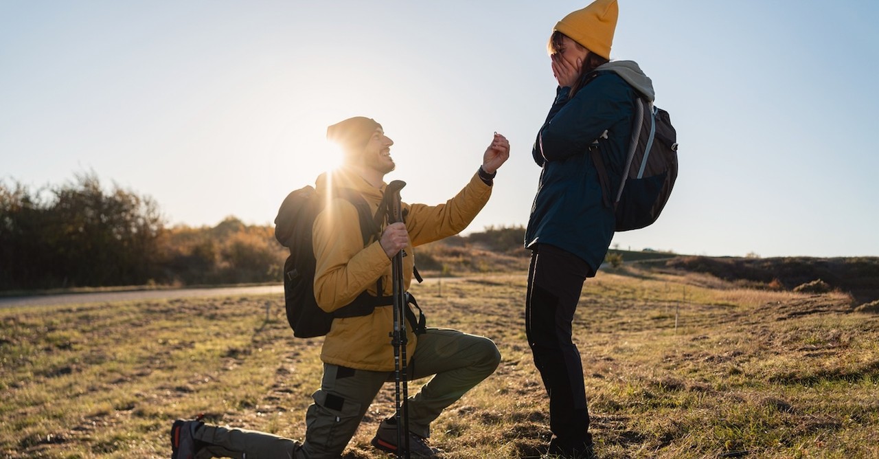 Man on knee proposing proposal on hike