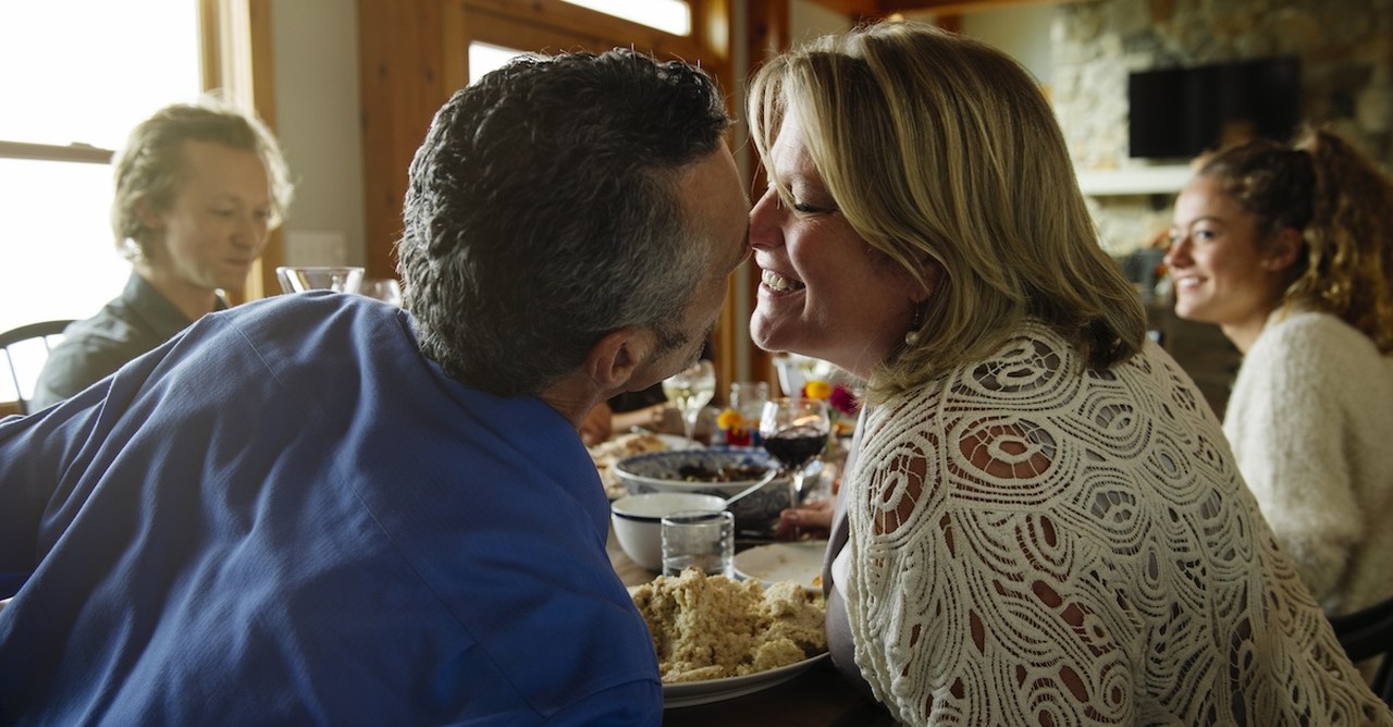 Happy married couple at thanksgiving table kissing thankful