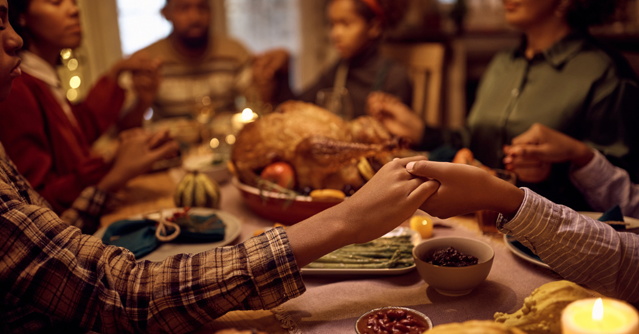family praying thanksgiving dinner table