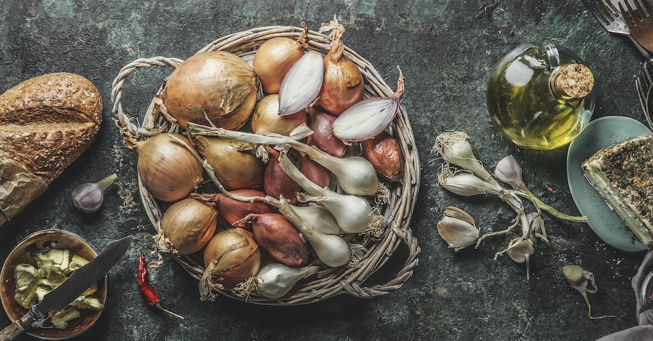 basket of garlic bulbs on a cooking surface counter with olive oil next to it