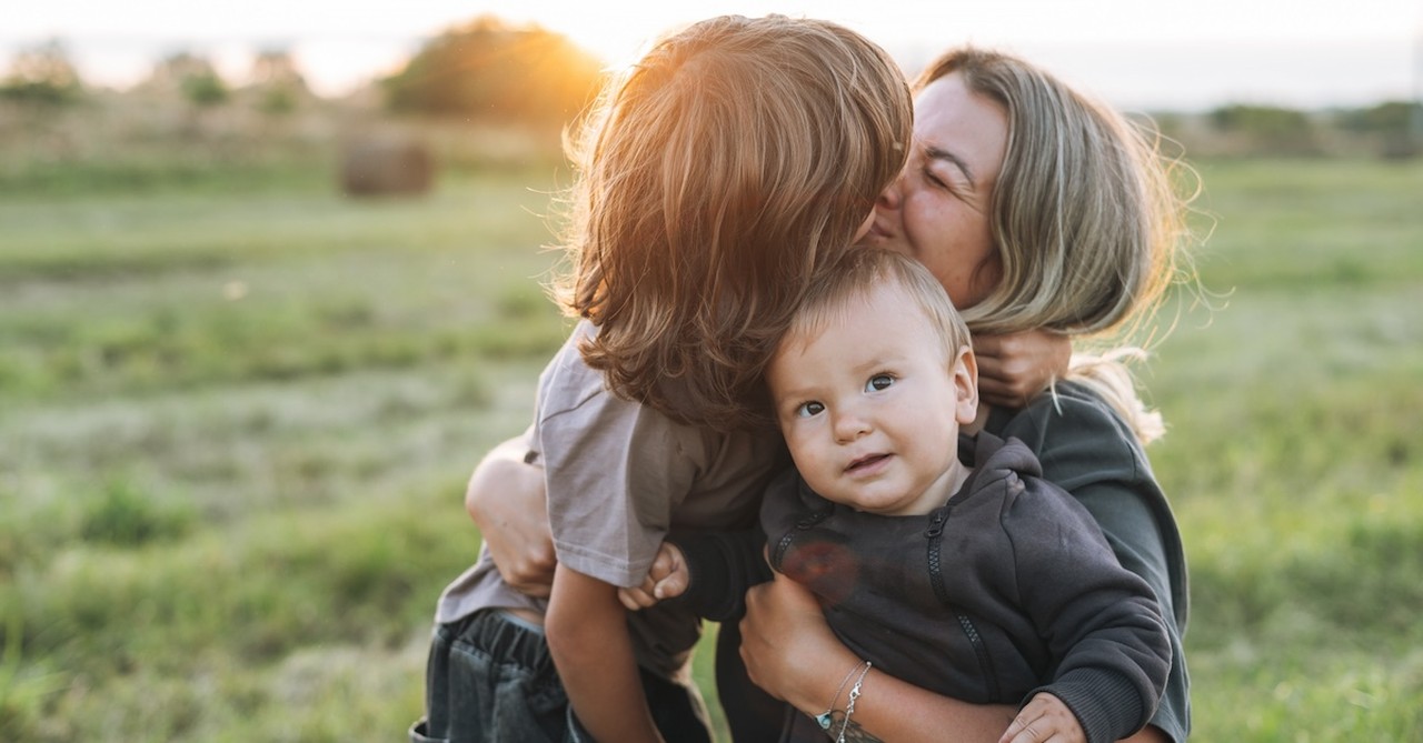 Mom and children sons outside hugging baby mother