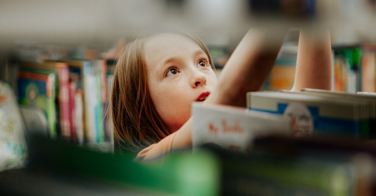 Girl in library picking out a book reading