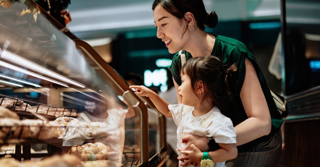 Mom and daughter toddler at coffee shop bakery picking out treat